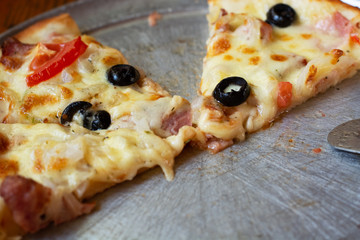 A piece of hot pizza on a metal mold. Leftover Pizza