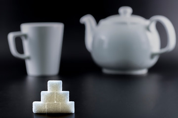 Sugar cubes were arranged in triangles. Background with white and patterned hearts. Black background.