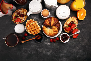 Huge healthy breakfast on table with coffee, orange juice, fruits, waffles and croissants. Good morning concept.