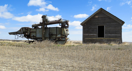 Fototapeta premium A horizontal of abandoned threshing machine and sittind beside is a old grainer.
