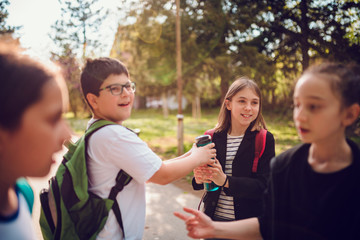 Boy fighting with girl over water bottle at schoolyard