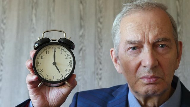 Senior Man In Suit Shows Alarm Clock 17:00 5:00 Am Pm.