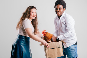 Funny interracial couple with chiken in box isolated on white background.