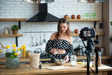 Pretty young woman girl food blogger in polka dot dress working on a new video and explaining how...