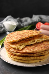 Homemade tortillas, located on a plate on a dark background, in the background sour cream, sausages and tomatoes