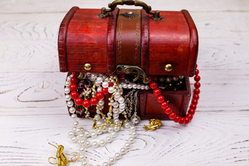 Vintage treasure chest full of jewelry and accessories on white wooden background