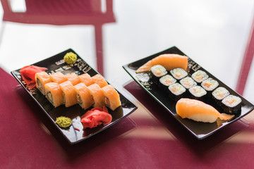 Sushi set with fresh fish on a plate on a glass table.