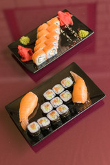 Sushi set with fresh fish on a plate on a glass table.