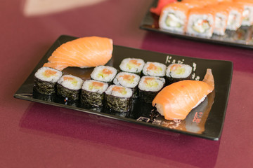Sushi set with fresh fish on a plate on a glass table.