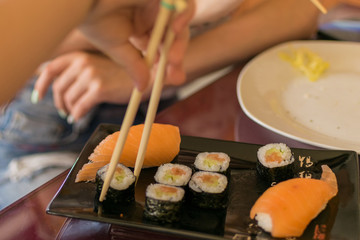 Obraz na płótnie Canvas A hand with chopsticks takes sushi.