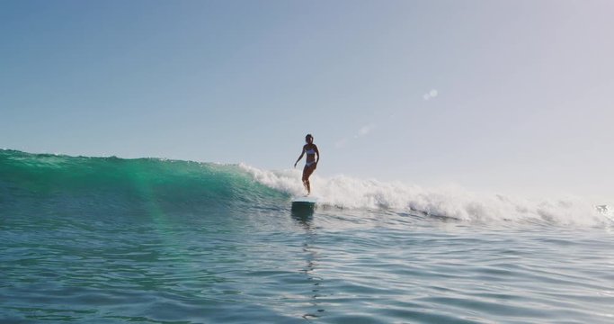 Happy young woman longboard surfing on summer vacation, beautiful woman surfing in the sun