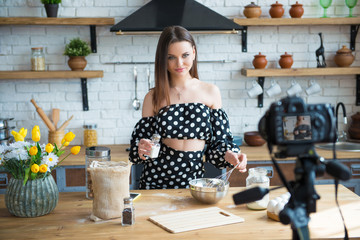 Pretty young woman girl food blogger in polka dot dress working on a new video and explaining how to cook a dish
