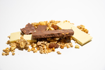 Side view on pile of granola/ muesli spilled among white. brown chocolate bars isolated on white background. Balanced and healthy diet concept.