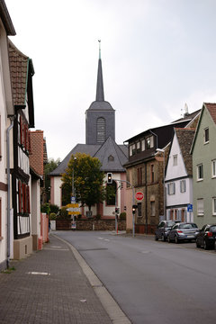 Der Turm der Marienkirche in Bischofsheim am Ende einer Hauptverkehrsstra&szlig;e mit angrenzenden Wohnh&auml;usern...