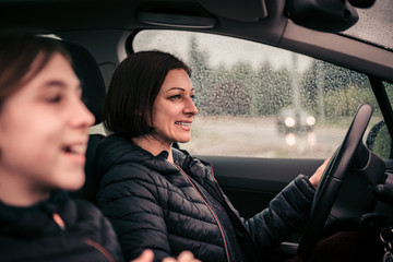 Mother driving daughter in passenger seat on a rainy day