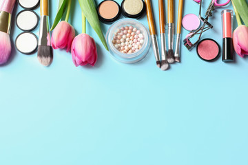 Makeup products and flowers on color background, flat lay with space for text