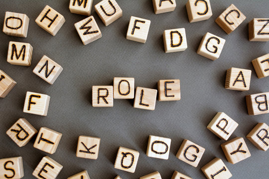 the word role wooden cubes with burnt letters, the role of people in society and their status, gray background top view, scattered cubes around random letters
