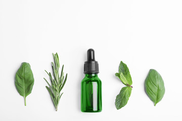 Little bottle of essential oil with different herbs on white background, top view