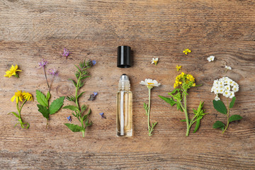 Flat lay composition with essential oil and flowers on wooden table
