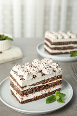 Plate of tiramisu cake on grey table, space for text