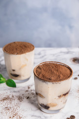 Two glasses of tiramisu cake on table against color background