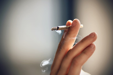 Human elegantly holds in the fingers of a hand Smoking a cigarette, illuminated of natural bright light