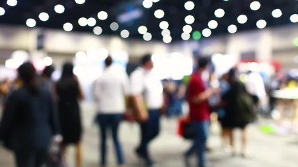Many business people walking in exhibition events or fairs. Blurred, defocused background of public hall, Bokeh light in event or conference hall background with blurry visitors concept. 