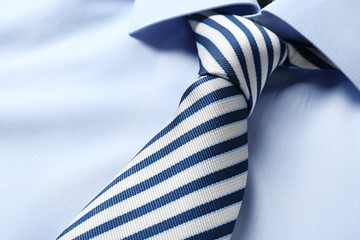 Striped male necktie on blue shirt, closeup - obrazy, fototapety, plakaty