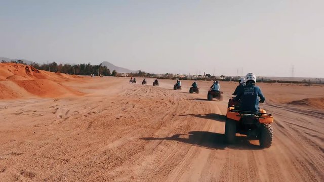 Group of quad bike racers driving in desert