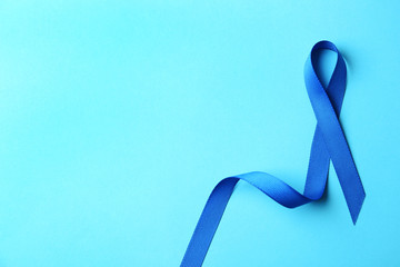 Blue ribbon on color background, top view with space for text. Colon cancer awareness concept