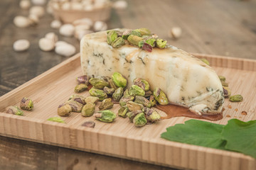 Charcuterie Cheese Board with Pistachios on Wooden Farm Table with Fresh Herbs