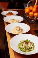 Row of various italian pasta: carbonara, bolognese, pesto penne on a table