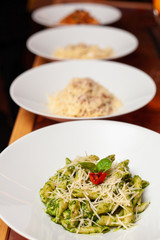 Row of various italian pasta: carbonara, bolognese, pesto penne on a table