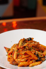 Close-up view of vegetarian penne arrabiata with tomato sauce, olives and eggplant