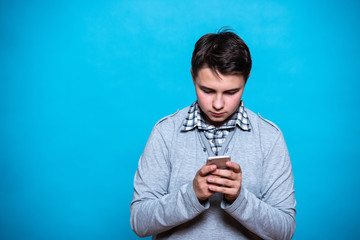 Boy schoolboy student teenager with a mobile phone in hand isolated on blue background