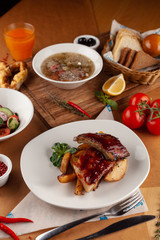 Close up of bbq fried ribs in a spicy sauce with baked potato, served in a white dish and as a part of nutritious set meal in a restaurant