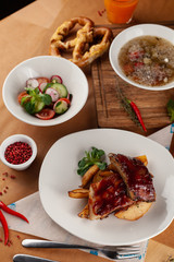 Close up of bbq fried ribs in a spicy sauce with baked potato, served in a white dish and as a part of nutritious set meal in a restaurant