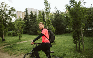 A handsome young man riding a bicycle in the park