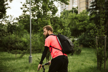 Naklejka premium A handsome young man riding a bicycle in the park