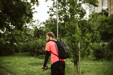 A handsome young man riding a bicycle in the park