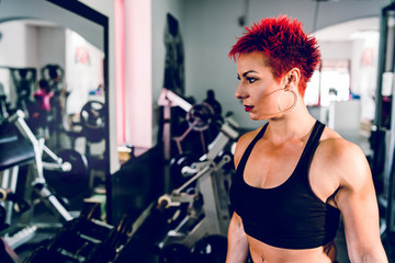 Young muscular strong woman holding dumbbells at the gym bodybuilding weight lifting fitness...
