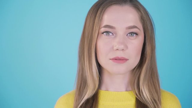 Close-up portrait. Calm girl on a blue background. Isolated background. Place for inscription left 4K
