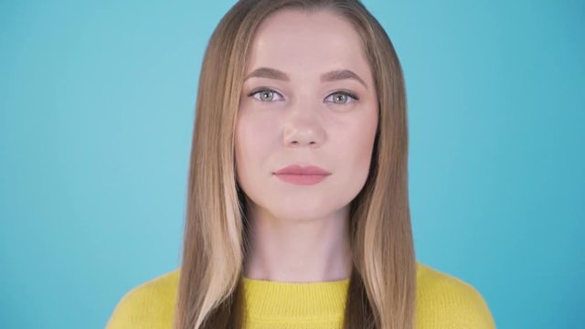 Close-up portrait. Calm girl on a blue background. Isolated background. 4 K