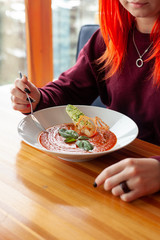 Woman is eating vegetarian tomato soup with basil and croutons