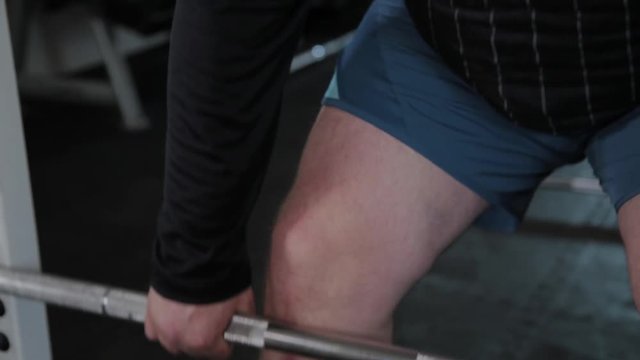 Adult man with overweight performs deadlift in the gym.