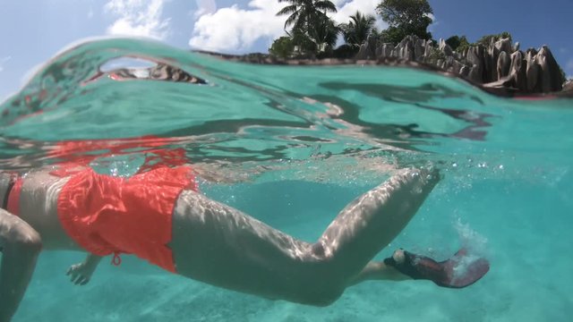 Close up of a girl snorkeling underwater at St. Pierre Island of Seychelles. woman exploring sea life of Indian Ocean, under and above water video photography.
