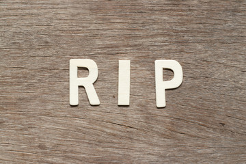 Alphabet letter in word RIP (abbreviation of rest in peace) on wood background