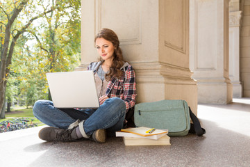 Young woman female college university student with earbuds studying using laptop computer