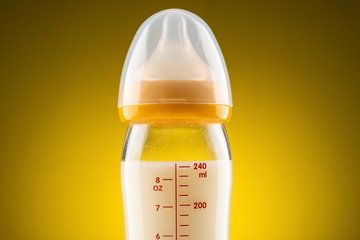 backlit glass baby bottle with powdered milk closeup on the upper part