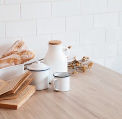 The table with a book, a cup of coffee, a jar of milk and a French bread with sunshine in morning, Beauty concept of beverage and food with relaxation and refreshment during day. Cafe shop.